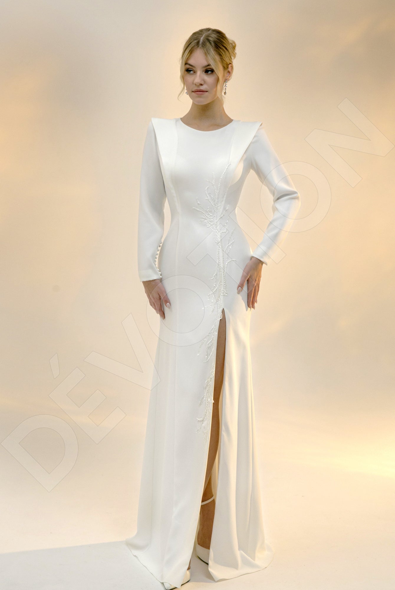 A radiant bride in a sleek sheath column light ivory wedding dress with a jewel neckline.